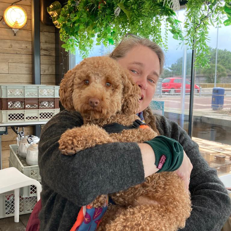 Gillian Jones holding Togi, a medium dog who is looking at the camera